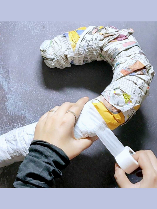 When Candy Cane shape is well rounded with the help of newspaper, Now we will wrap it with masking tape.
